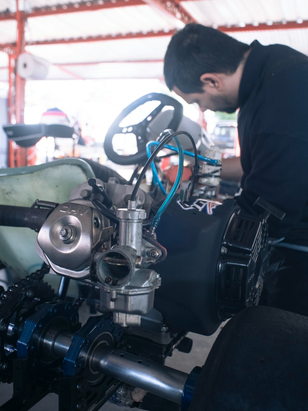 Mechanic working on go-kart engine in workshop.