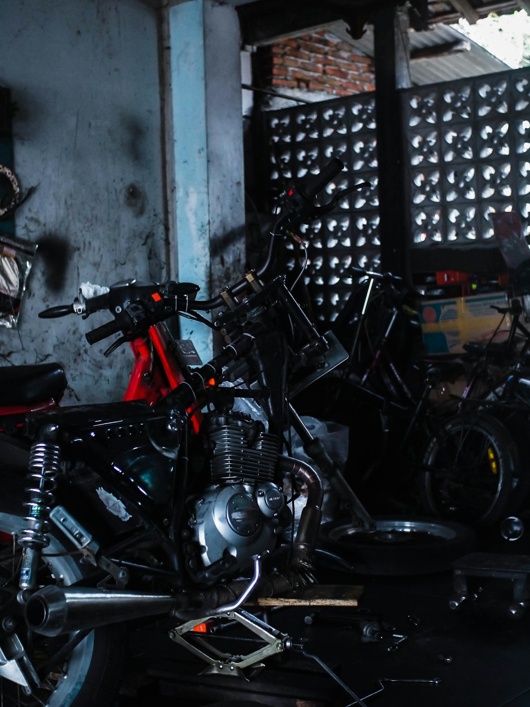 Motorcycle engine and red frame undergoing repairs in a garage.